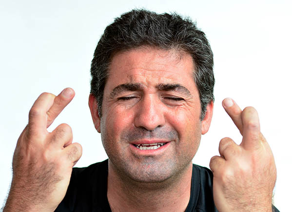 Mature man with crossed fingers hoping for good luck